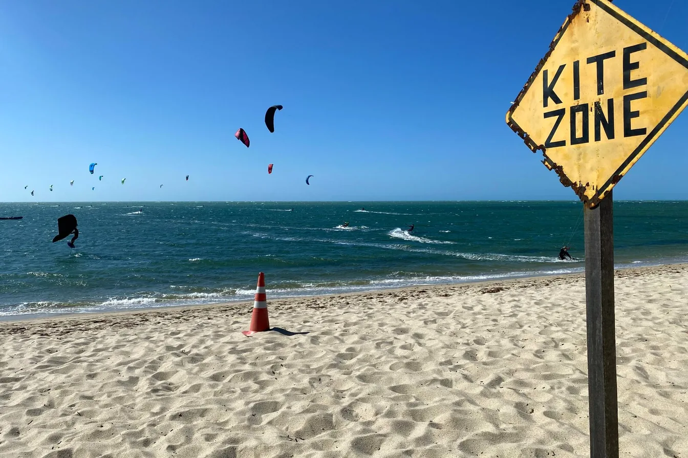 Área de velejo em Barra Grande, no Piauí, com kites no mar e sinalização do pico na areia